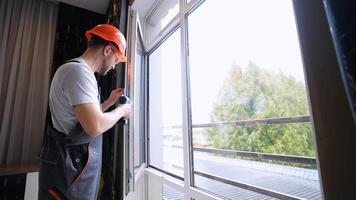 Workman in overalls installing or adjusting plastic windows in room at home video