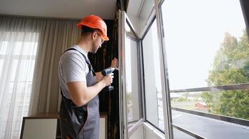 Workman in overalls installing or adjusting PVC windows in hotel room video