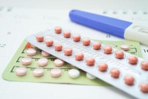 Pregnancy test and birth control pills on calendar, contraception health and medicine. photo