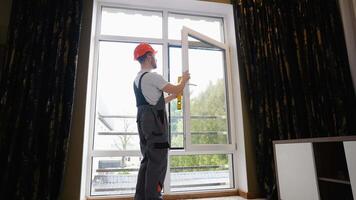 Window installer adjusting plastic windows with level tool in room video
