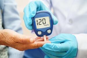 Doctor use digital glucose monitor measure and test stripe for check diabetes from finger blood sugar level. photo
