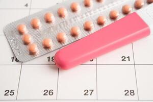 Pregnancy test and birth control pills on calendar, contraception health and medicine. photo