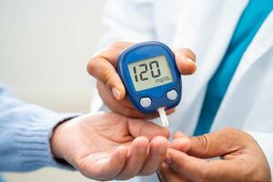 Doctor use digital glucose monitor measure and test stripe for check diabetes from finger blood sugar level. photo