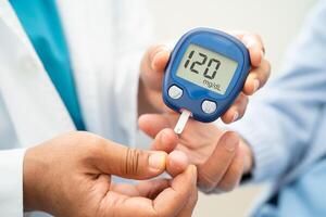 Doctor use digital glucose monitor measure and test stripe for check diabetes from finger blood sugar level. photo