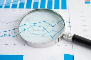 Magnifying glass on graph. Finance business and trading. photo