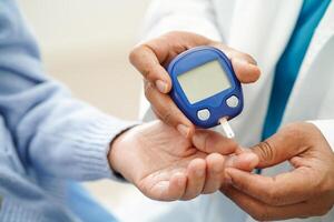 Doctor use digital glucose monitor measure and test stripe for check diabetes from finger blood sugar level. photo