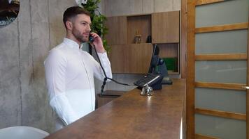 Friendly receptionist talking on phone at counter in hotel video