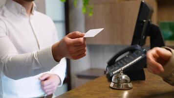 Receptionist gives card keys to the guest in hotel lobby, close up video