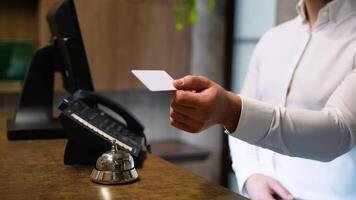 Receptionist gives card keys to the guest in hotel lobby, close up video