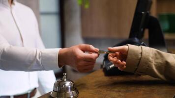 Receptionist gives keys to the guest in hotel lobby, close up video