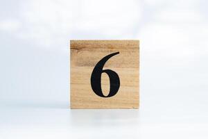 The number six written on a wooden cube, on a white background photo