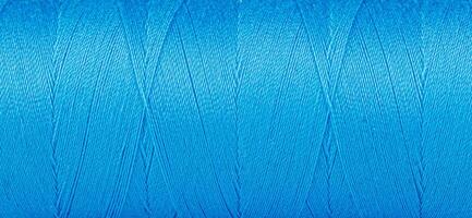 Texture of threads in a spool of blue color on a white background photo