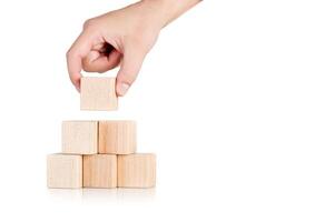 wooden cubes in the form of a pyramid with a hand on an isolate white background photo