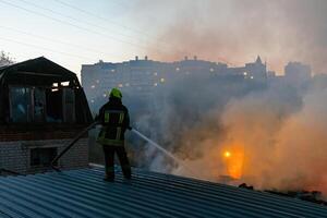Firefighter extinguish fire in house using spraying hose photo