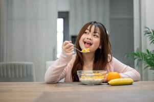 A young, cute Asian girl is having breakfast, enjoying eating a bowl of cereal at a dining table. photo
