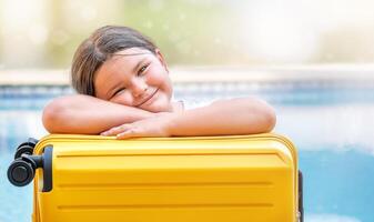 Portrait of a child with a suitcase near the pool photo