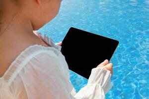 A tablet with copy space in the hands near the swimming pool photo