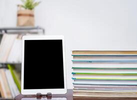 Tablet and stack of books on table photo