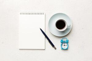 Modern office desk table with notebook and other supplies with cup of coffee. Blank notebook page for you design. Top view, flat lay photo