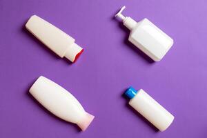 Set of White Cosmetic containers isolated on colored background, top view with copy space. Group of plastic bodycare bottle containers with empty space for you design photo