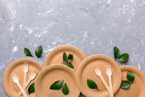 set of empty reusable disposable eco-friendly plates, cups, utensils on light white colored table background. top view. Biodegradable craft dishes. Recycling concept. Close-up photo