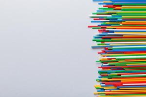 Heap of colorful plastic drinking straws on Colored background, flat lay. Copy Space for text photo