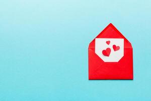 Red paper envelope with empty white card and heart on colored background. top view valentines day concept photo