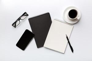 Modern office desk table with notebook, smartphone and other supplies with cup of coffee. Blank notebook page for you design. Top view, flat lay photo