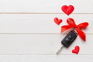 Car key with a red bow and a heart on Colored table. Giving present or gift for valentine day or christmas, Top view with copy space photo
