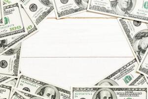 Frame made of dollars with copy space in the middle. Top view of business concept on white wooden background with copy space photo