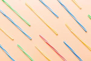 many multi-colored plastic tubes for cocktail on Colored background, top view photo