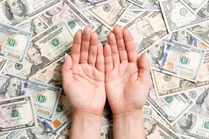 Top view of female hands on various dollar background. Wealth concept with empty space for your design. Begging money concept photo
