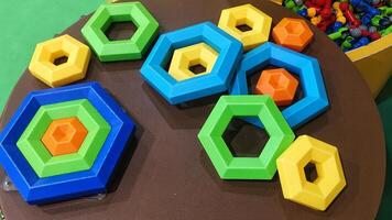 Colorful hexagonal stacking toy pieces in various sizes, designed for children's play and learning, placed on a brown table photo