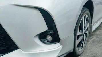 Close-up view of a modern white car's front fog light and tire, showcasing its sleek design photo