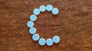 White bottle caps creatively arranged in the shape of the letter A on a wooden textured background for abstract design photo