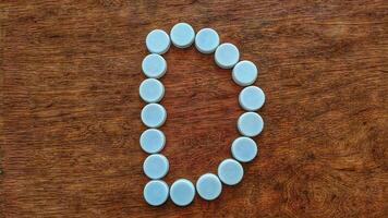 White bottle caps creatively arranged in the shape of the letter D on a wooden textured background for abstract design photo