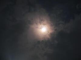 A mesmerizing shot of a full moon glowing through a cloudy night sky, creating a mystical and serene atmosphere photo