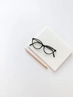 Photography with a minimalist workspace with a blank notebook, glasses and pencil creating a tranquil atmosphere photo
