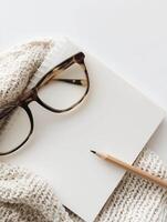 Photography with a minimalist workspace with a blank notebook, glasses and pencil creating a tranquil atmosphere photo