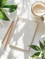 Photography with a serene workspace with a blank notebook, a cup of coffee, and greenery creating a tranquil atmosphere photo