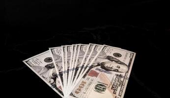 A stack of one hundred dollar bills on a black surface photo