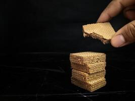 A person holding a waffle with a piece of chocolate on top photo