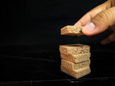 A person is placing a piece of wood on top of a stack of bricks photo