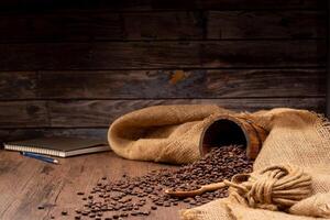 The picture of coffee beans stacked together on a wooden floor in a warm, light atmosphere, on a dark background, with copy space. photo