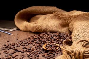 The picture of coffee beans stacked together on a wooden floor in a warm, light atmosphere, on a dark background, with copy space. photo