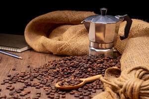 The picture of coffee beans stacked together on a wooden floor in a warm, light atmosphere, on a dark background, with copy space. photo