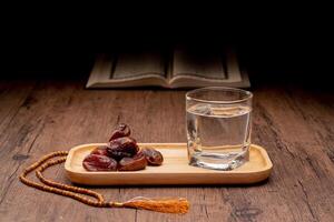 Many Date Palms are on bowls and cups of water and the Quran is on wooden tables, to wait for the time of Iftar, with the concept of ramadan Muslims around the world. photo