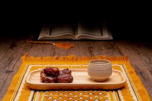 Many Date Palms are on bowls and cups of water and the Quran is on wooden tables, to wait for the time of Iftar, with the concept of ramadan Muslims around the world. photo