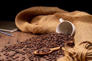 The picture of coffee beans stacked together on a wooden floor in a warm, light atmosphere, on a dark background, with copy space. photo