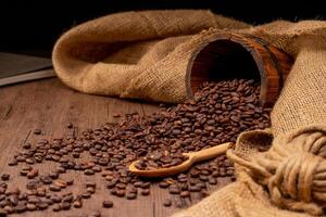 The picture of coffee beans stacked together on a wooden floor in a warm, light atmosphere, on a dark background, with copy space. photo